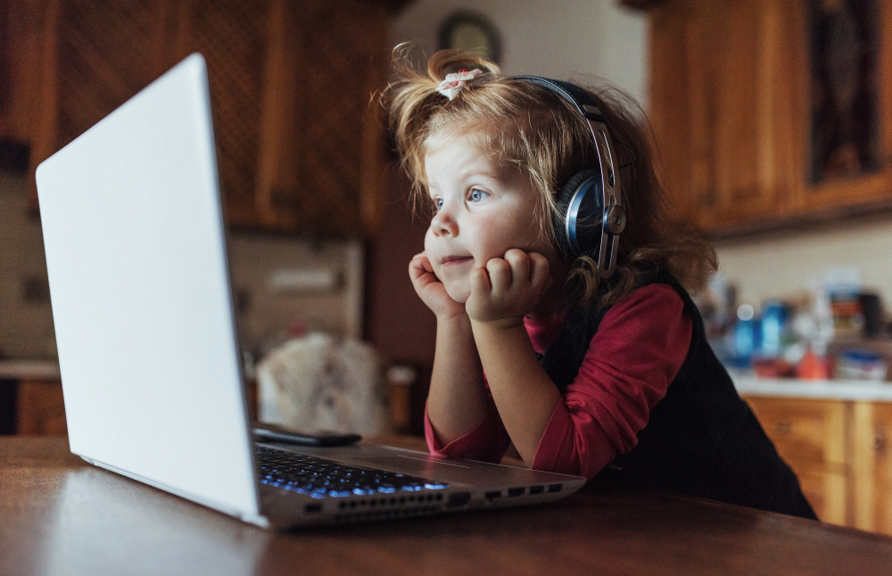 Litet barn med hörlurar som ser på en laptop