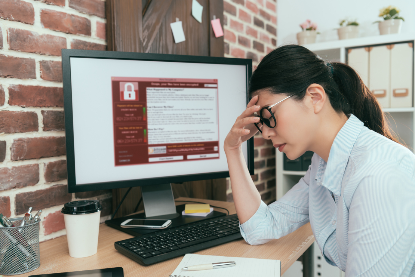 Kvinna som sitter vid sin dator och utsatts för en ransomware-attack